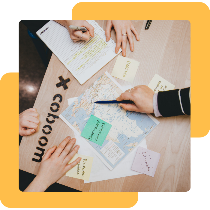 Une table avec les mains de 3 personnes prenant des notes avec les mentions Co-création, participation, entreprise responsabilisée, sur des post-it